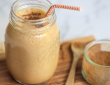 Pumpkin Pie Smoothie in a mason jar next to a bowl on cinnamon